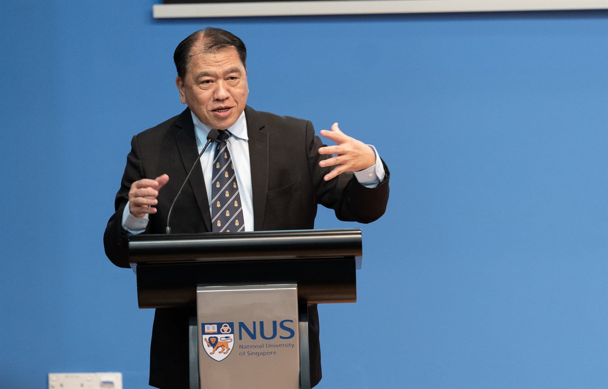 Dr Neo Kok Beng speaking at a lectern during his opening address at DEAI 2026